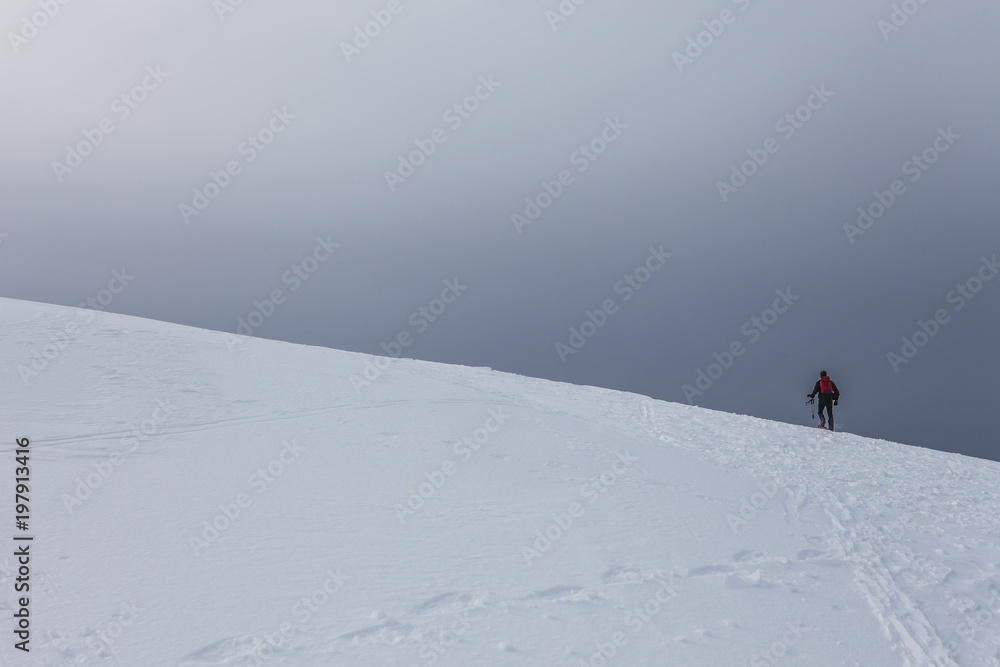 Lone alpinist walking on a snow-covered slope, Col Visentin, Belluno, Italy