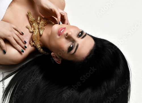 Young beautiful brunette woman lying on the floor wear expensive gold crocodile jewellery with long hair 