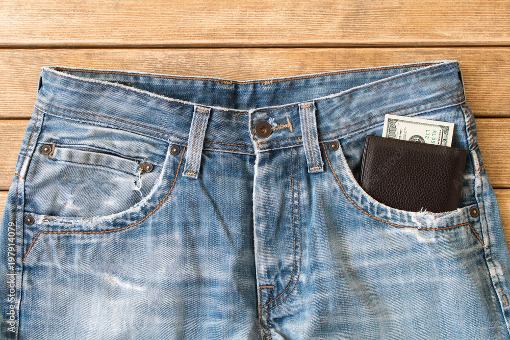 Blue jeans with a wallet in your front pocket on a wooden background . The view from the top Blue jeans with a wallet in your front pocket on a wooden background . The view from the top