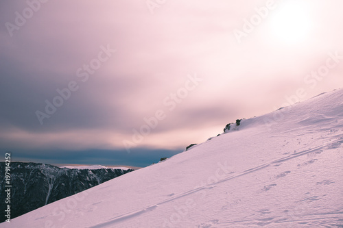 Snowy slope with mountain and pale sun in the background, Col Visentin, Belluno, Veneto, Italy