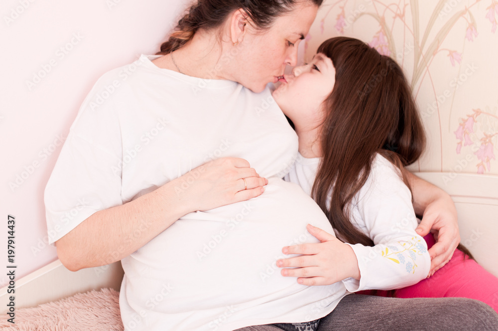 Close-up of a pregnant woman with a child touching her belly, the concept of expecting a child and family Close-up of a pregnant woman with a child touching her belly, the concept of expecting a child and family