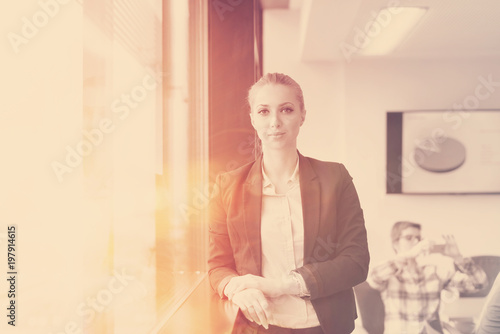 portrait of young business woman at office with team on meeting in background