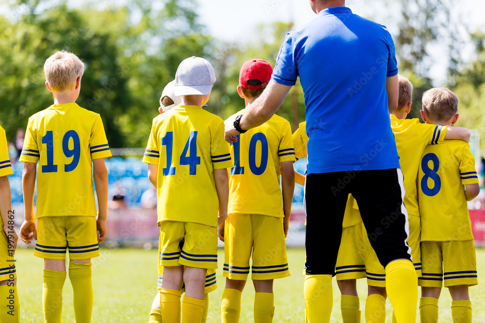 Youth football coach talking to childrens soccer team. Young football players with coach. Soccer