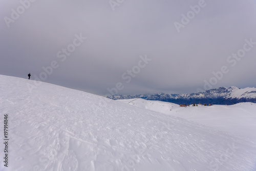 Lone alpinist on a snow-covered slope, with the Dolomite peaks in the background, Copl Visentin, Belluno, Italy photo