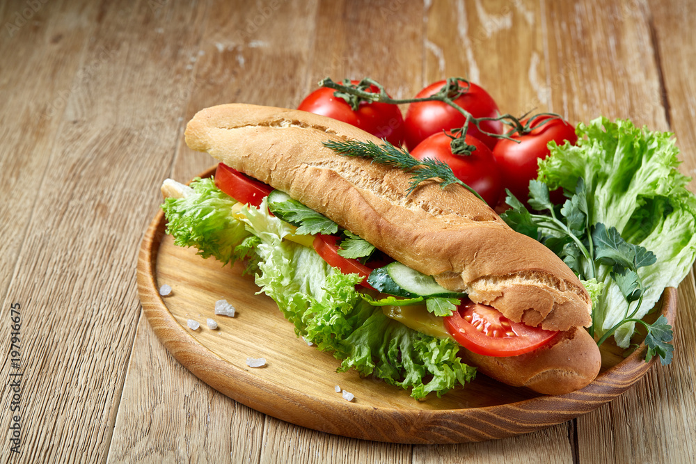 Fresh sandwich with lettuce, tomatoes and cheese served on wooden plate over rustic background, selective focus Fresh sandwich with lettuce, tomatoes and cheese served on wooden plate over rustic background, selective focus