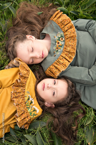 portrait of girls in retro dresses lying on the grass one upside down with a pensive look of delight and reverence photo