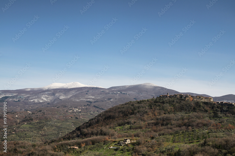 Obraz premium talian Countryside. Tuscany. Daylight. Blue Sky. Spring. Green Hills, a Peaceful Village, a Snowy Mountain in the Background