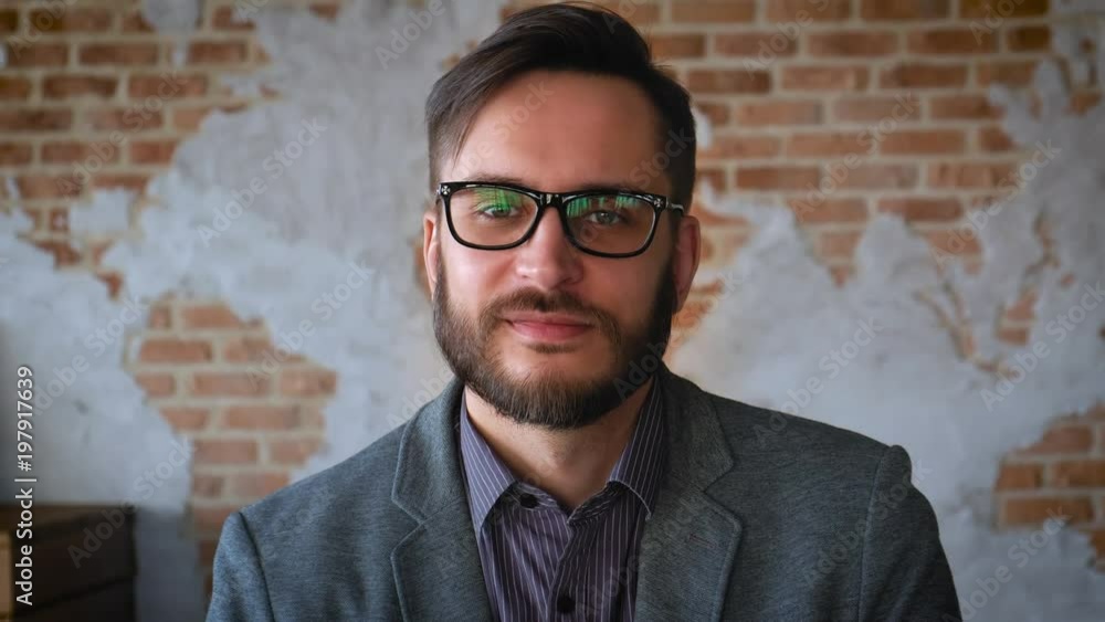 Portrait of successful Businessman entrepreneur working at busy office smiling. Portrait: Fashionable modern young man with a beard businessman smiling. It is located in a modern office in loft style.