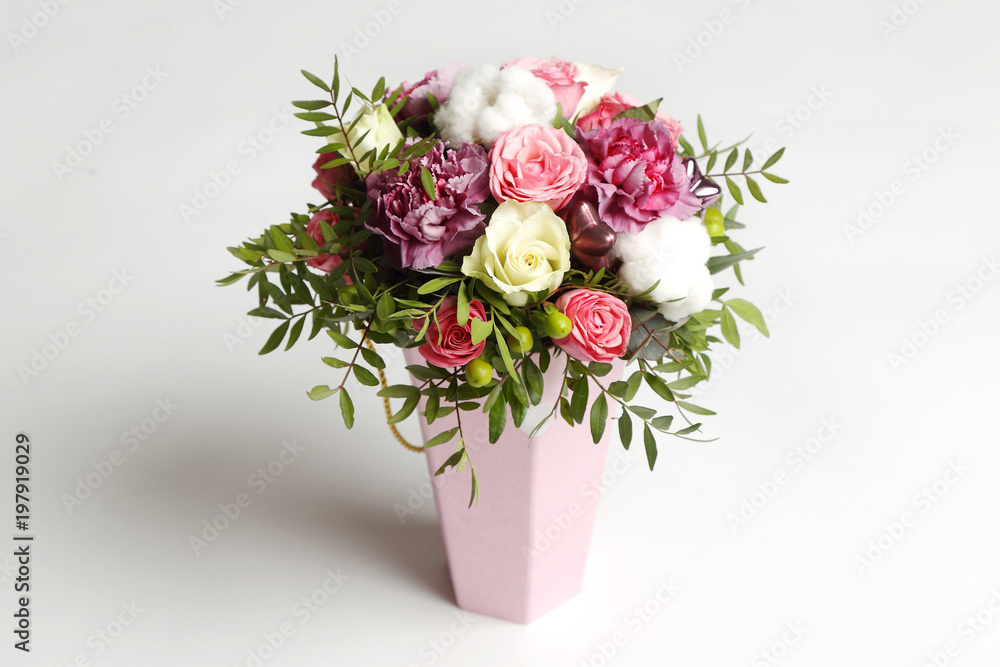 Beautiful bouquet of different flowers in a pink box on white background.