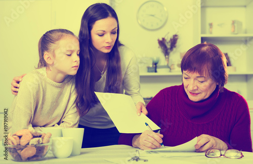 Adult daughter controlling signing of documents by grandmother photo