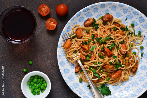 Spaghetti with mussels and green peas in tomato sauce with basil.