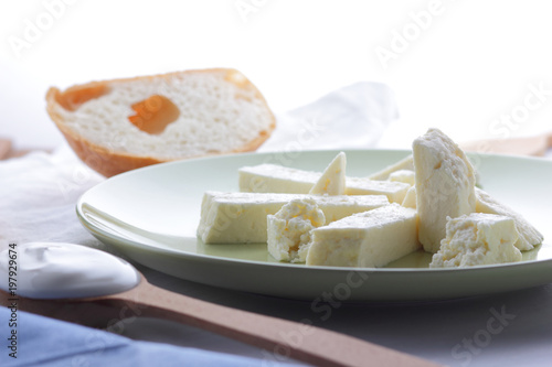 Cheese, honey and sour cream, a piece of bread, feta in a green plate, soft cheese on a white background, a wooden spoon with sour cream, French breakfast, blue napkin, honey in glassware, art
