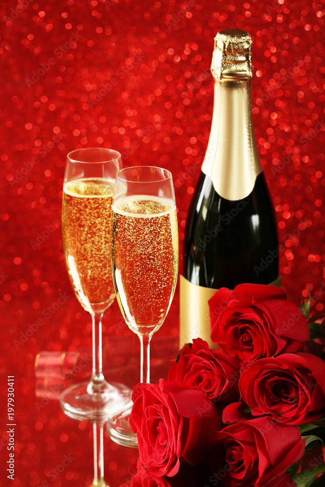 Champagne bottle with glasses and bouquet of red roses on lights background