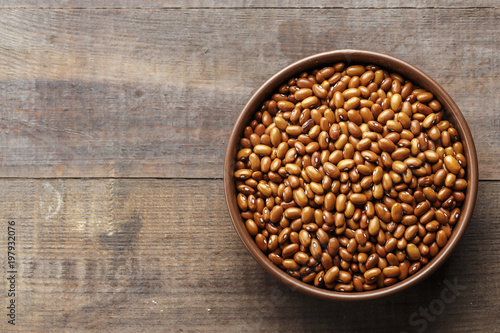 brown beans in a plate on a wooden background