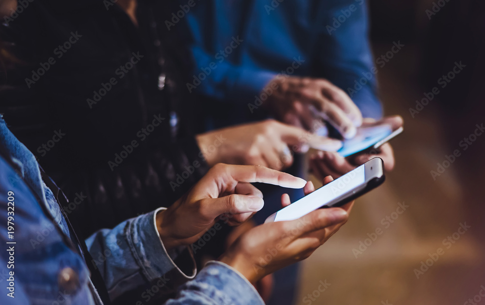 Bloggers together pointing finger on screen smartphone on background light in night atmospheric city, group adult hipsters friends using in hands mobile phone, street online wi-fi internet concept