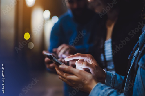 Bloggers together pointing finger on screen smartphone on background bokeh light in night city, group adult hipsters friends using in hands mobile phone, street online wi-fi internet concept