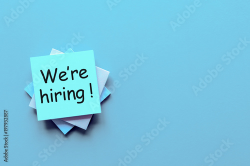 Job recruiting advertisement represented by 'WE ARE HIRING' texts at note. Image is used to represent the hiring position to be recruited and filled.
