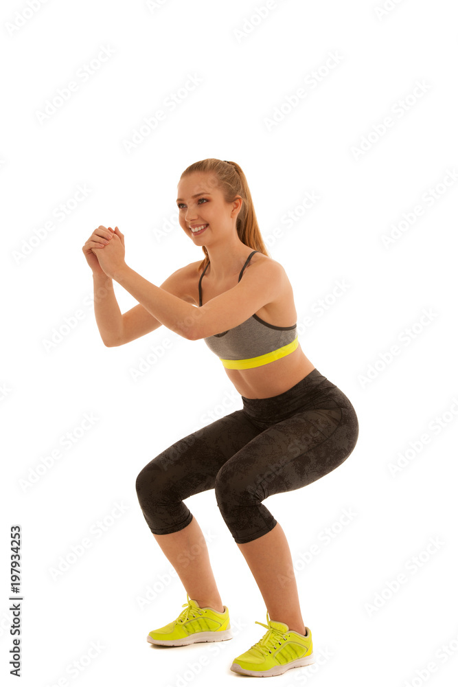 Beautiful young fit woman makes squats isolated over white background Beautiful young fit woman makes squats isolated over white background