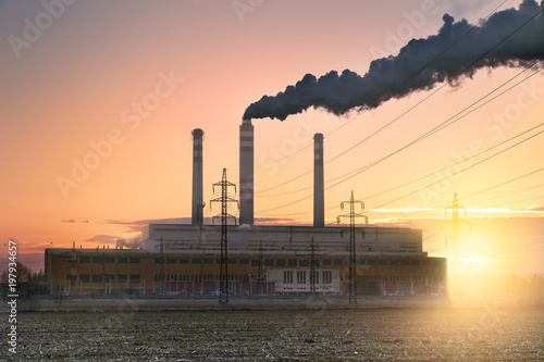 Coal power plant on sunrise. Chimneys with smoke and transmission lines
