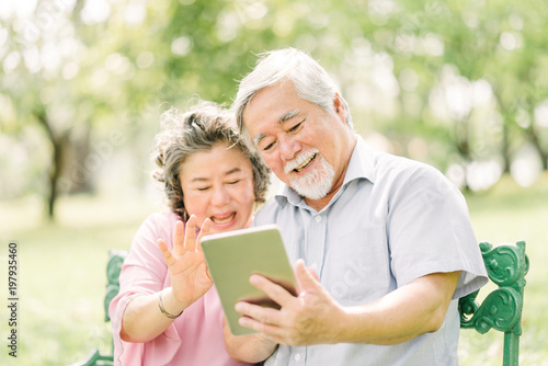 Happy senior Asian couple using tablet