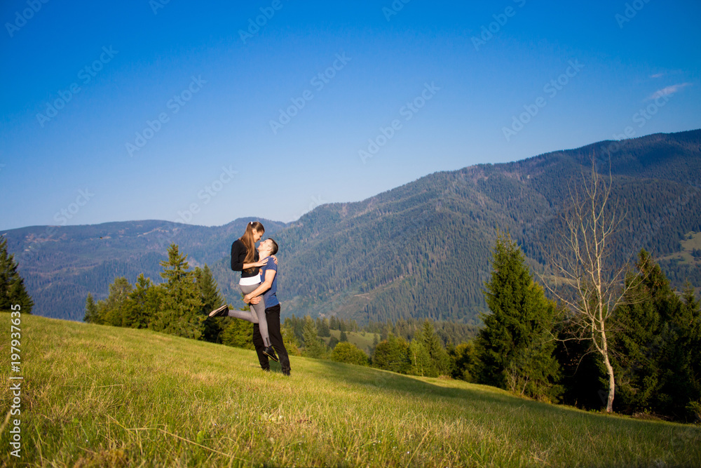 Tourist couple hugging on top of mountains with blue sky. Couple enjoying free happiness in beautiful landscape
