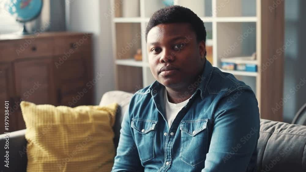 portrait young african american man look at camera eat chocolate face sit on sofa home close up slow motion attractive guy emotion indoors handsome happiness success casual sunlight cute big eyes portrait young african american man look at camera eat chocolate face sit on sofa home close up slow motion attractive guy emotion indoors handsome happiness success casual sunlight cute big eyes