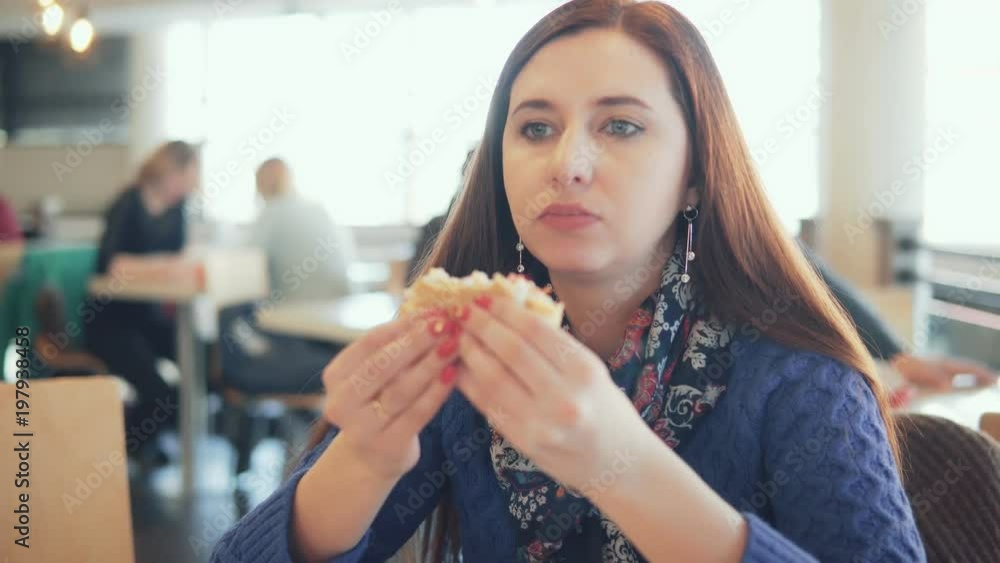 woman eating a hamburger in a cafe woman eating a hamburger in a cafe