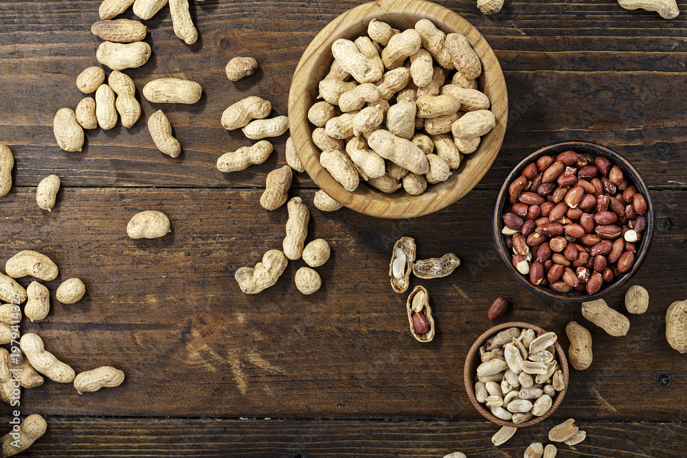 raw peanuts in a plate on a wooden background raw peanuts in a plate on a wooden background