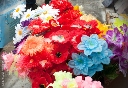 A bouquets of colored, artificial flower in the street. Decoration flowers for sell