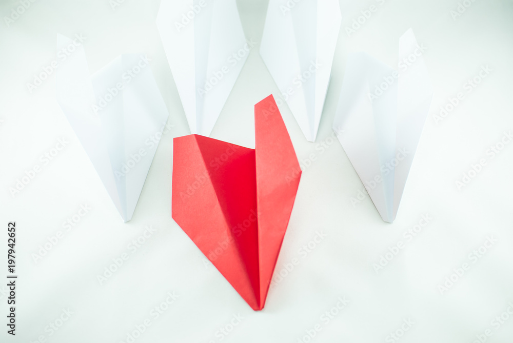 Red paper plane among white ones on a white background, isolated. Concept (idea) of airlines, freedom, leadership, success, and individualism. Red paper plane among white ones on a white background, isolated. Concept (idea) of airlines, freedom, leadership, success, and individualism.