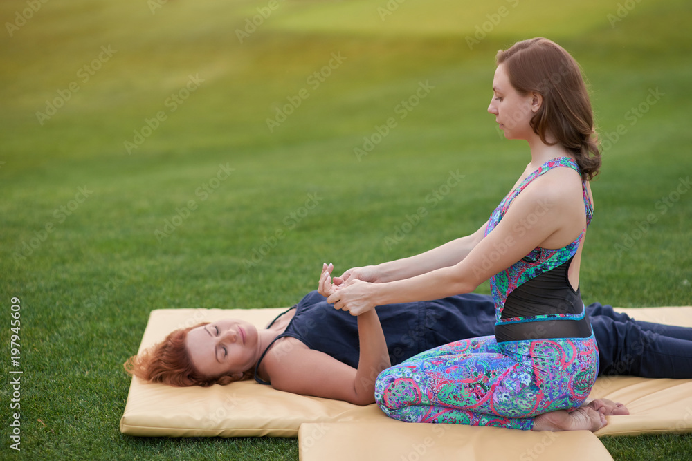 Lying relaxing woman getting hand massage. Outdoor thai massage on the lawn. Lying relaxing woman getting hand massage. Outdoor thai massage on the lawn.