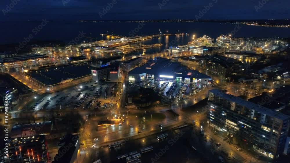 aerial view of the night city with street lighting and moving traffic near the sea and ships in the port aerial view of the night city with street lighting and moving traffic near the sea and ships in the port