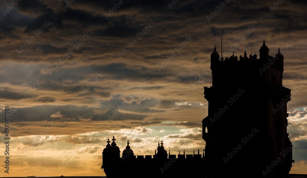 Belem Tower silhouette with ocean and dramatic sky at sunset, near Lisbon in Portugal