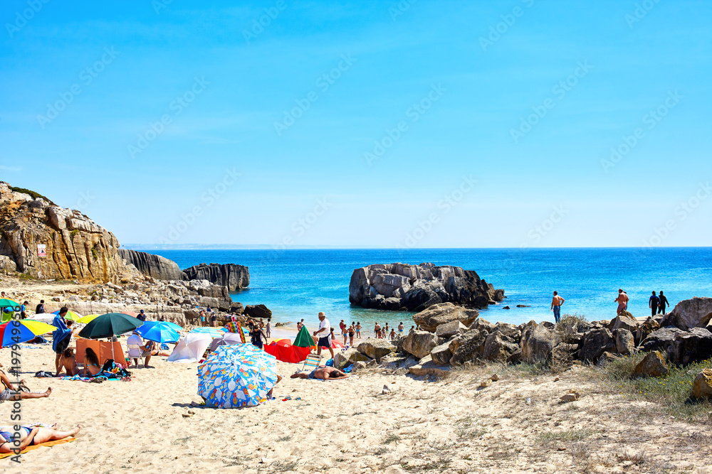 Colourful beach with people and cliff rocks in Peniche, Portugal