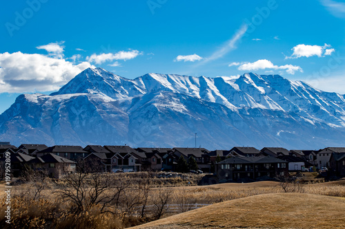 Landscape of fields and houses with the snow-capped Rocky Mountians in the background