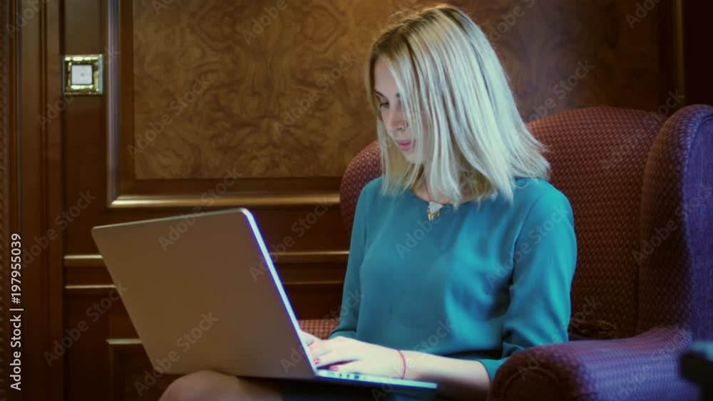 Beautiful woman working on notebook sitting at table in home office. Young woman using laptop computer for browsing internet in working studio Beautiful woman working on notebook sitting at table in home office. Young woman using laptop computer for browsing internet in working studio