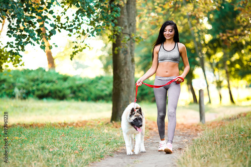 Sports woman walking with dog in the park.