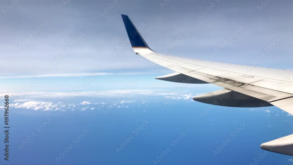 Wing of a plane overlooking blue ocean and clouds Wing of a plane overlooking blue ocean and clouds