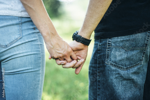 young couple staying in the mountains holding hands in jeans