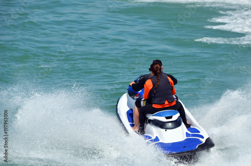 Young couple riding tandem on a blue and white jet ski.