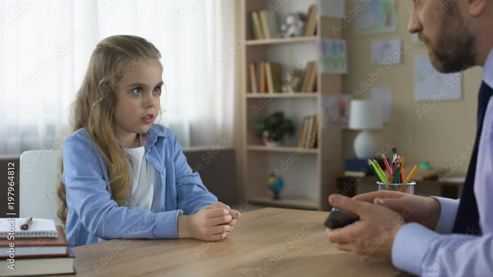 Little girl playing game on cellphone, dad taking phone away, gadget addiction Little girl playing game on cellphone, dad taking phone away, gadget addiction