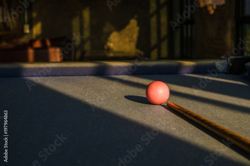 Close up pink snooker ball on foreground with low light.