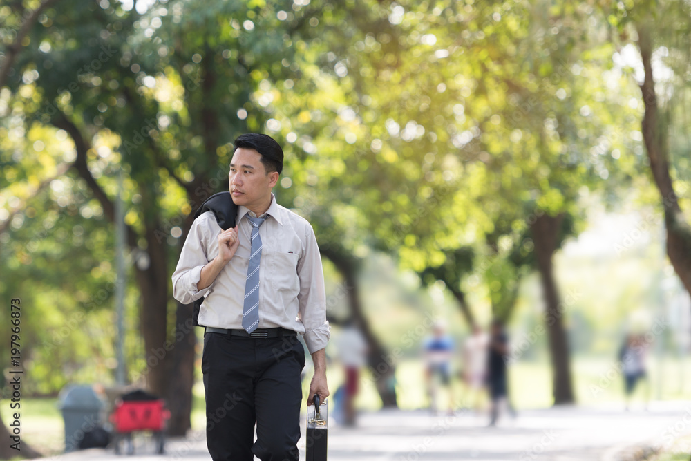 Young Asia businessman showing stress face. He was walking in the Park.. Young Asia businessman showing stress face. He was walking in the Park..