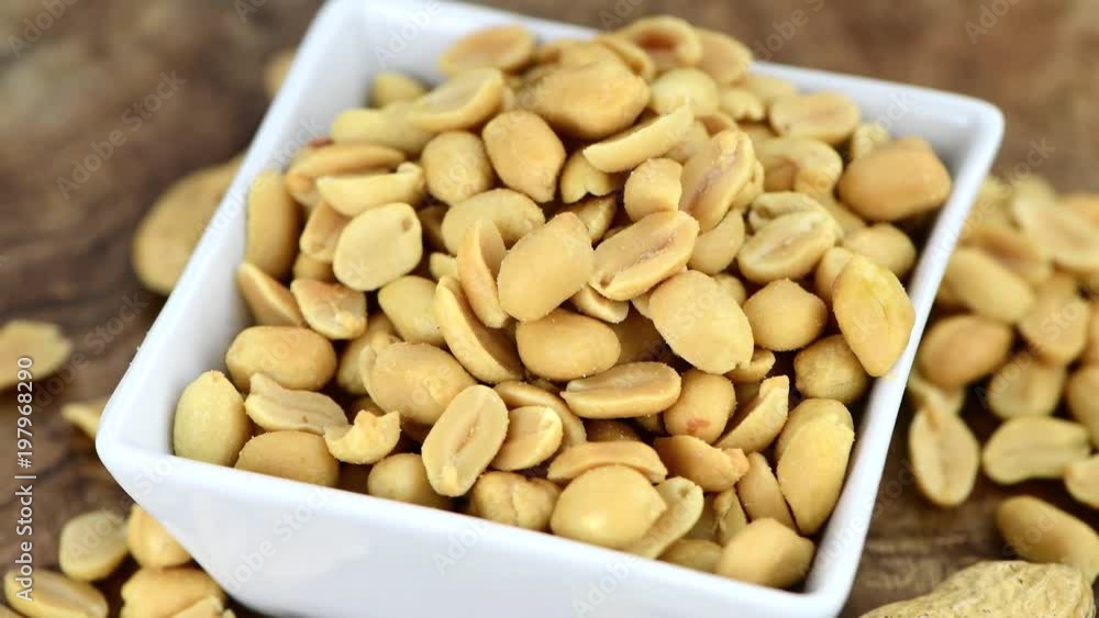 Roasted and salted Peanuts rotating on a wooden board (seamless looapble) in 4K UHD Roasted and salted Peanuts rotating on a wooden board (seamless looapble) in 4K UHD