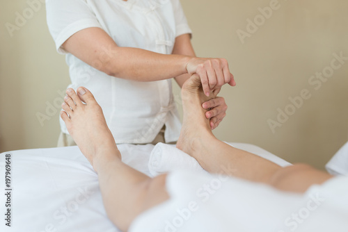 Asian girl relaxing having feet massage in a spa salon, close up view