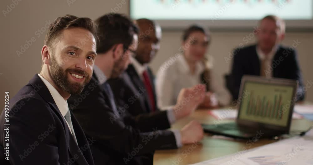 Portrait of a cheerful businessman in a board meeting with his colleagues. Portrait of a cheerful businessman in a board meeting with his colleagues.