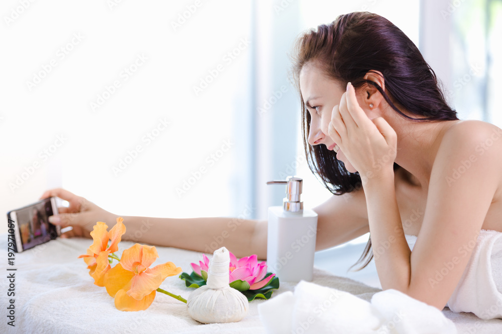 Beautiful young woman relaxing spa salon with selfi on mobile phone at spa resort Beautiful young woman relaxing spa salon with selfi on mobile phone at spa resort