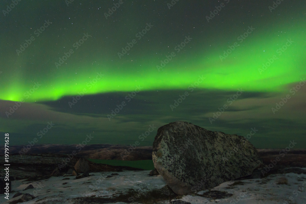 Northern Lights, polar lights over the hills and tundra in winter.Huge stone.