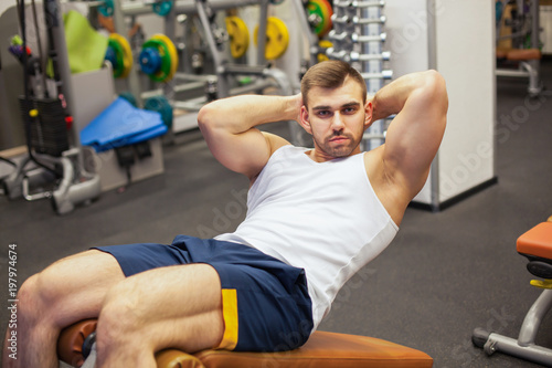 sport, fitness, bodybuilding, lifestyle and people concept - young man doing sit-up abdominal exercises Bench Press in gym