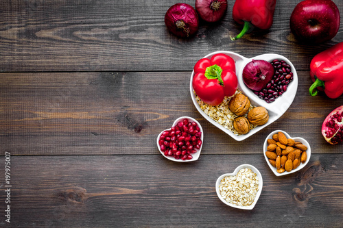 Food which help heart stay healthy. Vegetables, fruits, nuts in heart shaped bowl on dark wooden background top view copy space